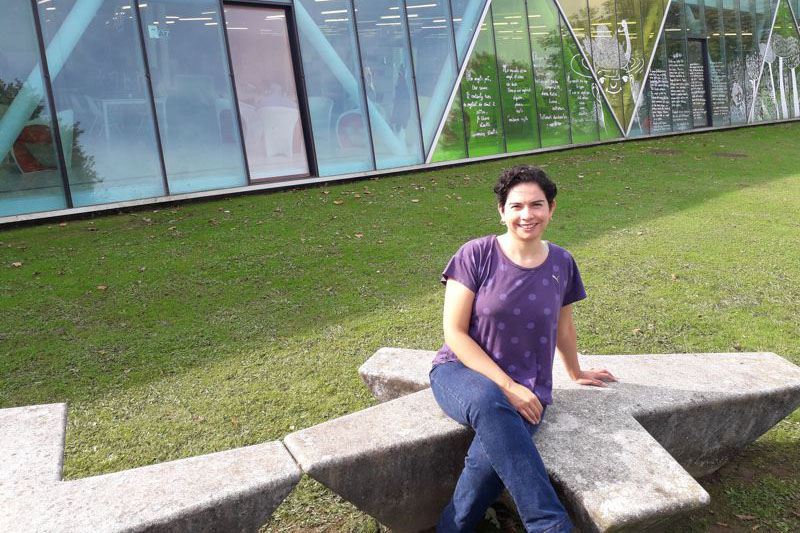 Foto de Marcela Vega sentada en un banco de piedra